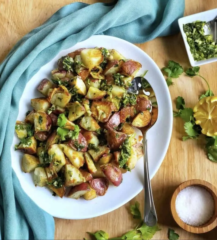 chimichurri potatoes in a serving dish topped with herbs