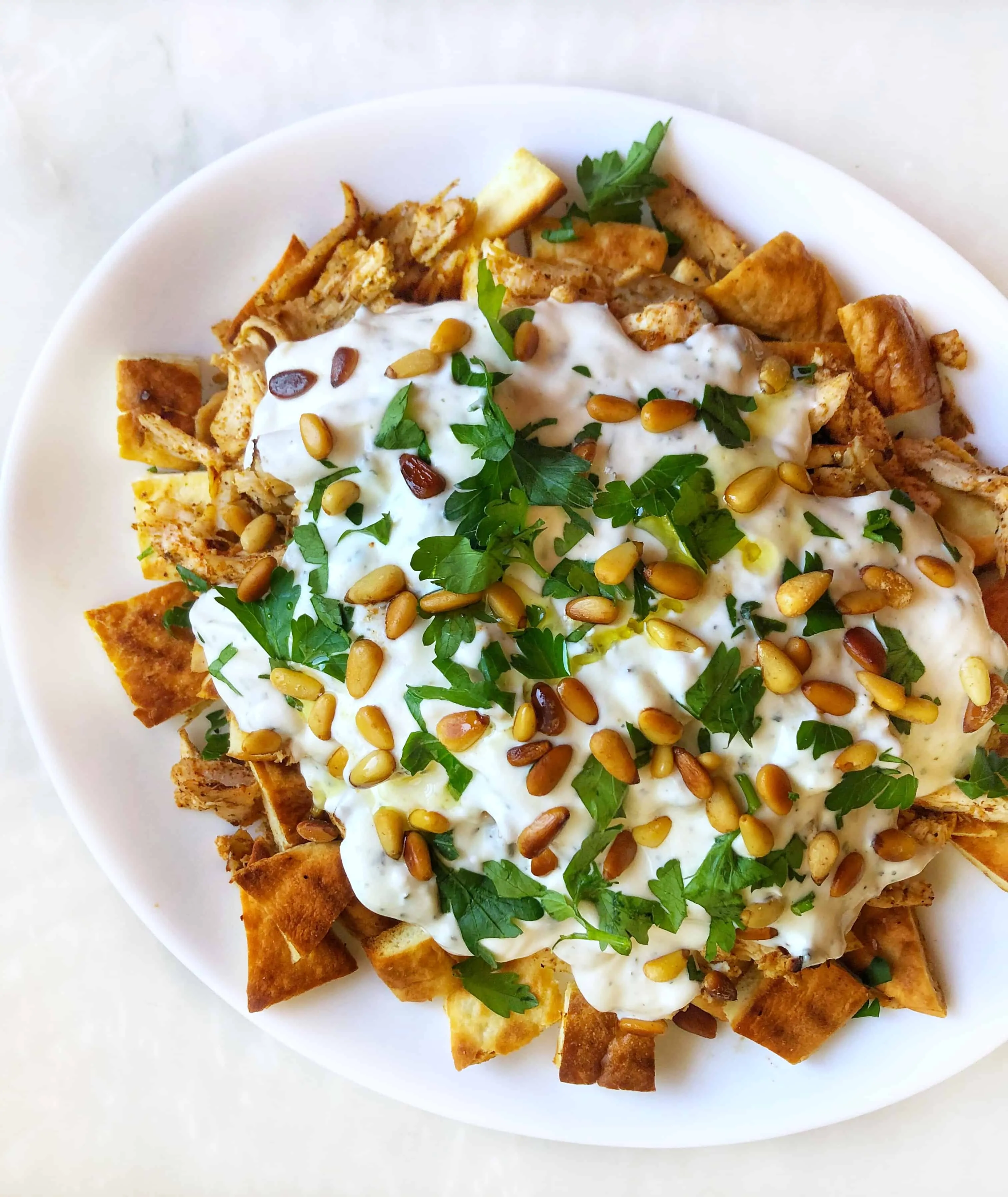 chicken fatteh topped with pine nuts