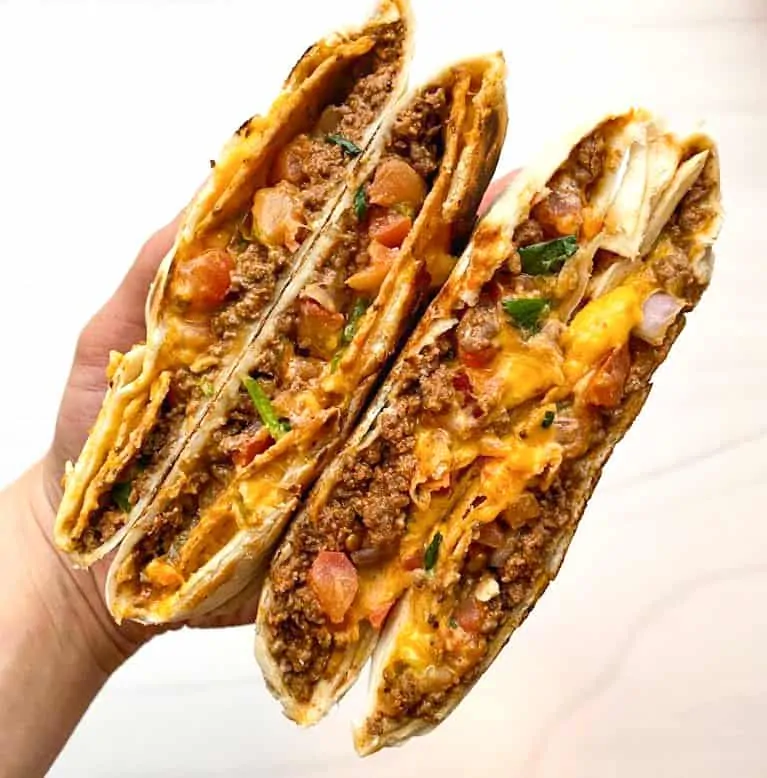 crunch wrap supreme cut in half showcasing the ground beef, cheese, and tomatoes.