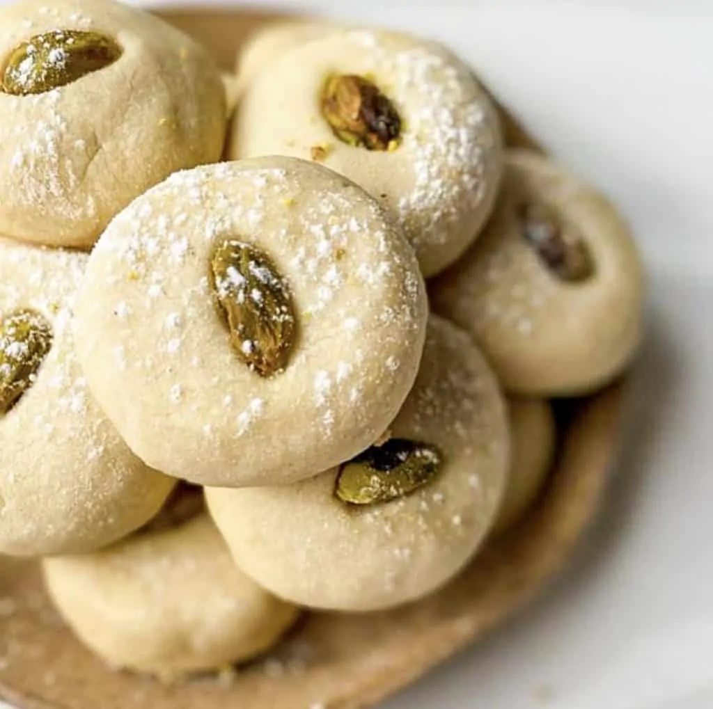 traditional ghraybeh (middle eastern shortbread cookies) sprinkled with powdered sugar with a pistachio in the center