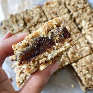hand holding a close up of a square of a date bar showcasing the date filling