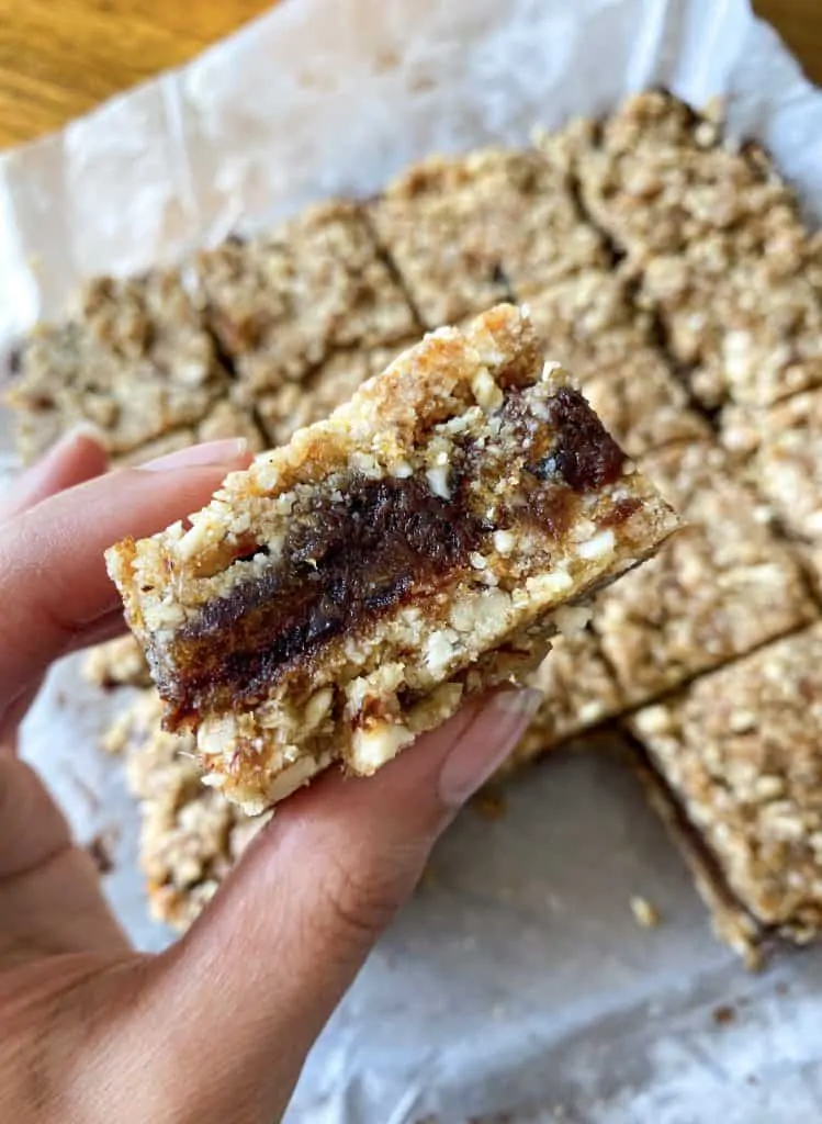hand holding a close up of a square of a date bar showcasing the date filling