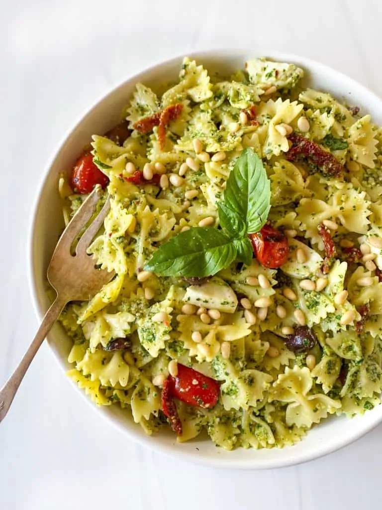 pesto pasta salad bowtie pasta with pine nuts and fresh basil on top