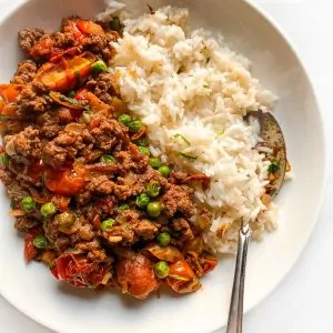 tomato beef saute on a plate with a side of white rice