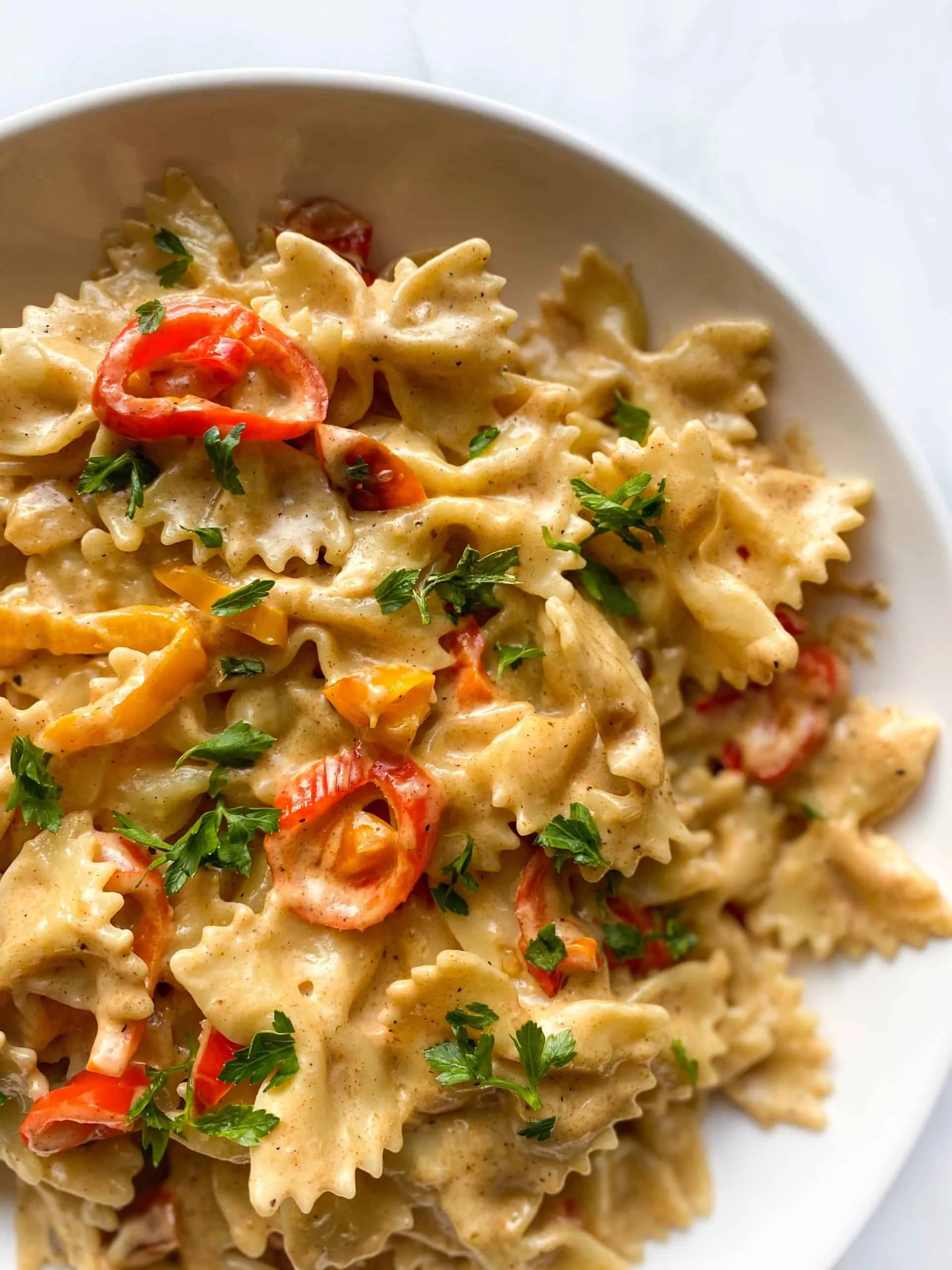 Cajun Creamy Pasta bow ties in a bowl with chopped pepper slices