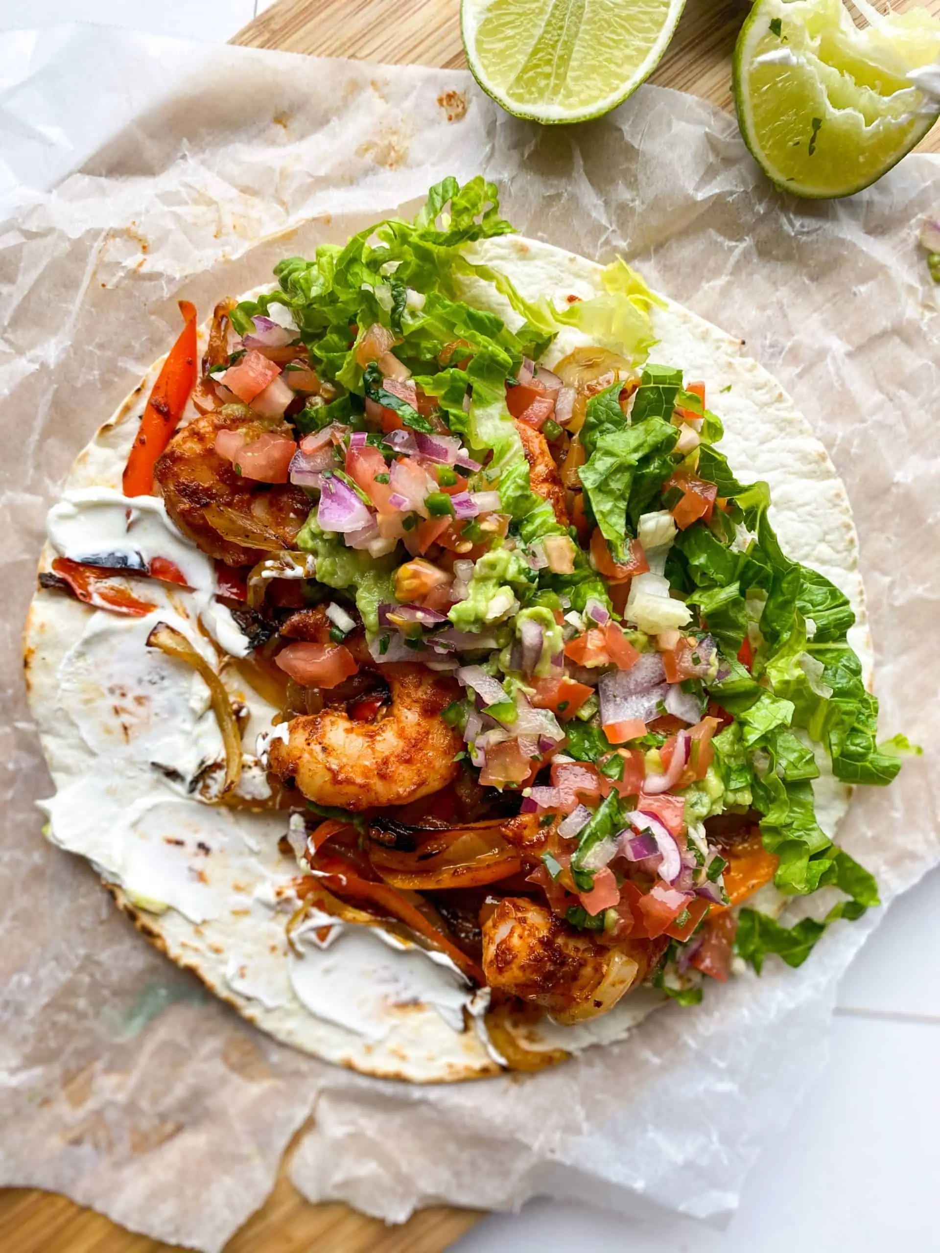Shrimp Fajitas on a parchment paper with a side of squeezed lime