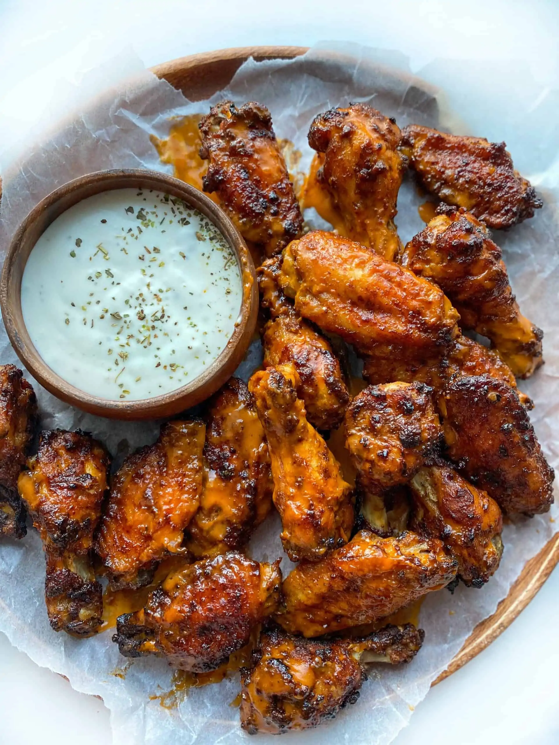 Air Fryer chicken wings on a parchment paper with a side of dipping sauce
