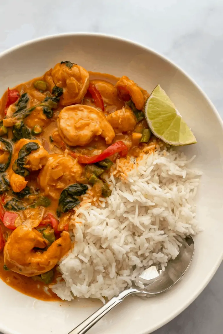 bowl of shrimp thai curry with a side of white rice and a lime