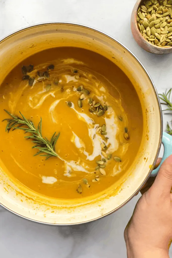 pot of butternut squash soup topped with fennel and pumpkin seeds