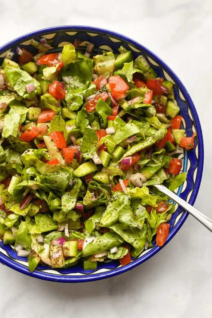 chopped lettuce, cucumbers, tomatoes, in a decorative bowl