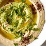 Easy authentic hummus recipe topped with sumac, parsley, jalapeno sauce, and olive oil.
