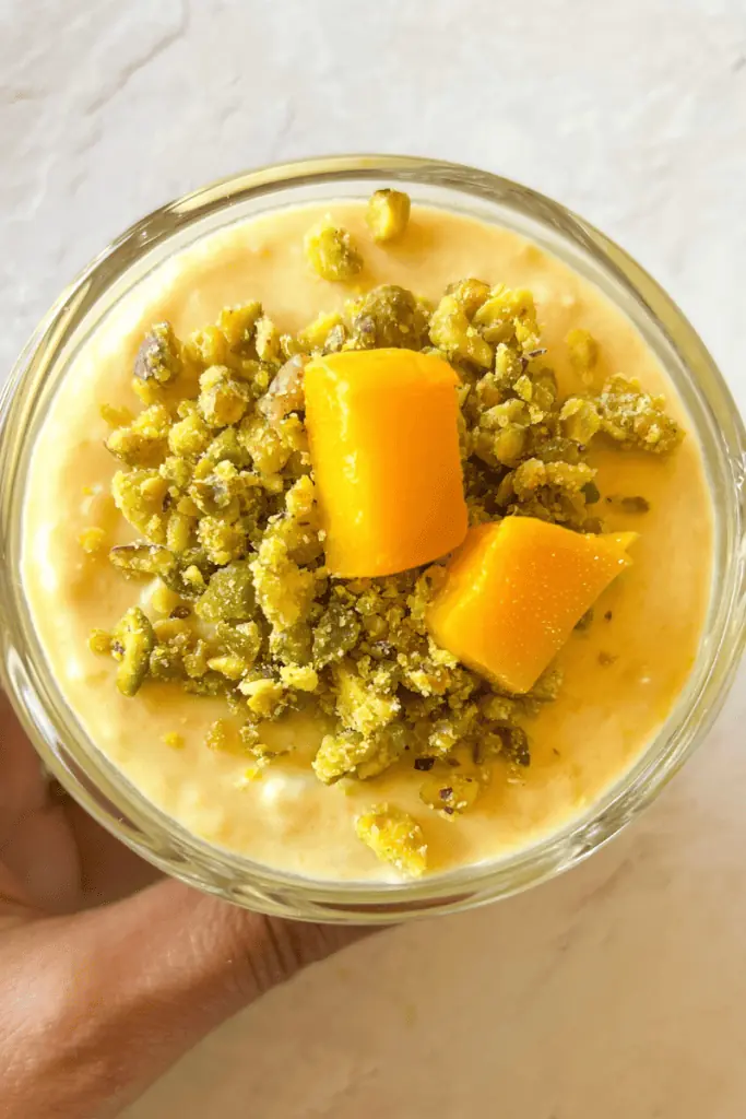 a head shot of the vegan mango coconut mousse displaying the pistachio crumble on top and fresh mango slices
