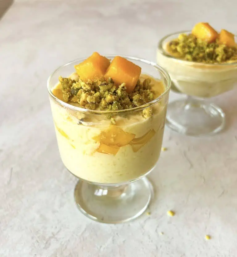 vegan mango coconut mousse cups filled with mango mousse and topped with pistachios and mangoes.