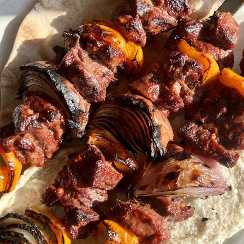 Middle eastern lamb skewers (lamb shish kebab) served on pita with charred onions and bell peppers