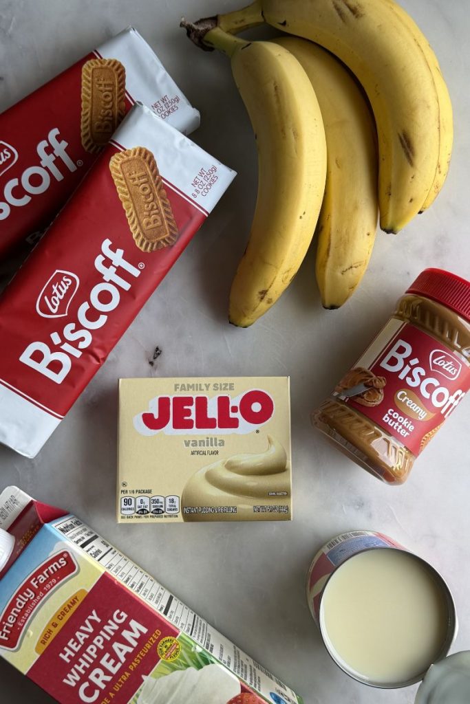 Ingredients for Biscoff banana pudding including Biscoff cookies, cookie butter, bananas, vanilla pudding mix, and heavy whipping cream